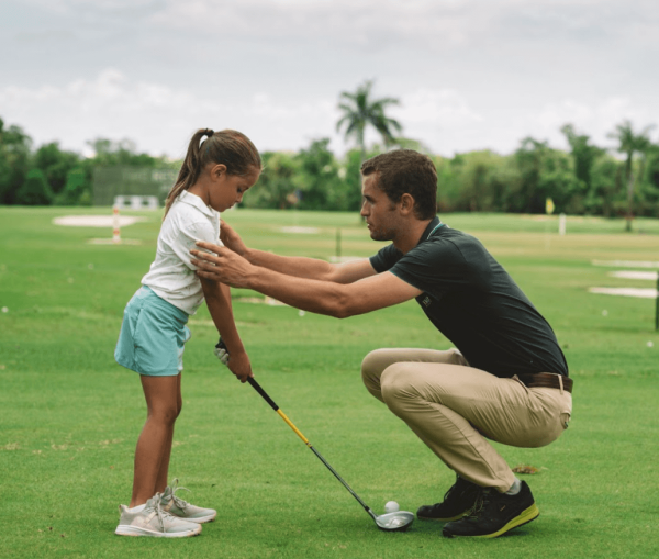 golf instructor positions girl at tee